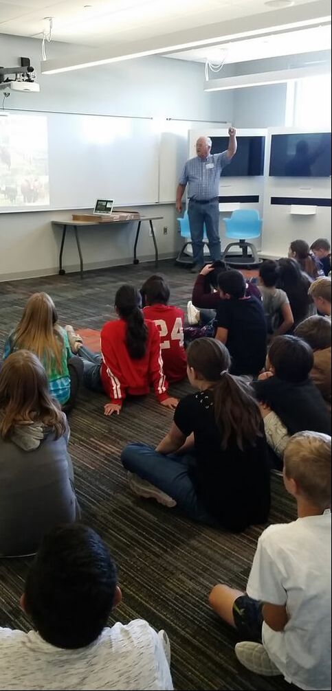 6th graders seated on the floor, listening to SCD Irrigation Water Management Specialist Jerry Allen, as he teaches about watershed conservation